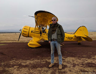 Anthony Bourdain standing in front of a yellow prop plane