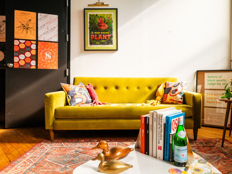 Green sofa with colorful pillows, art, and industrial interior