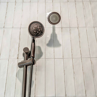 Tiled shower wall showing shower fixtures