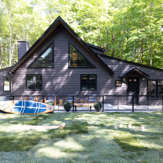 Exterior photo of the house with a paddle board on the porch.