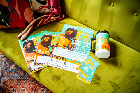 Stacked concert flyers and a mug on a green couch, featuring Becky Hill concert.