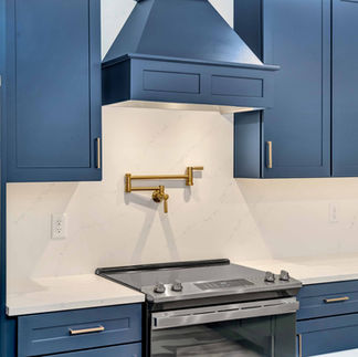 Blue Cabinetted kitchen, closer photo of the stove and hooded vent.