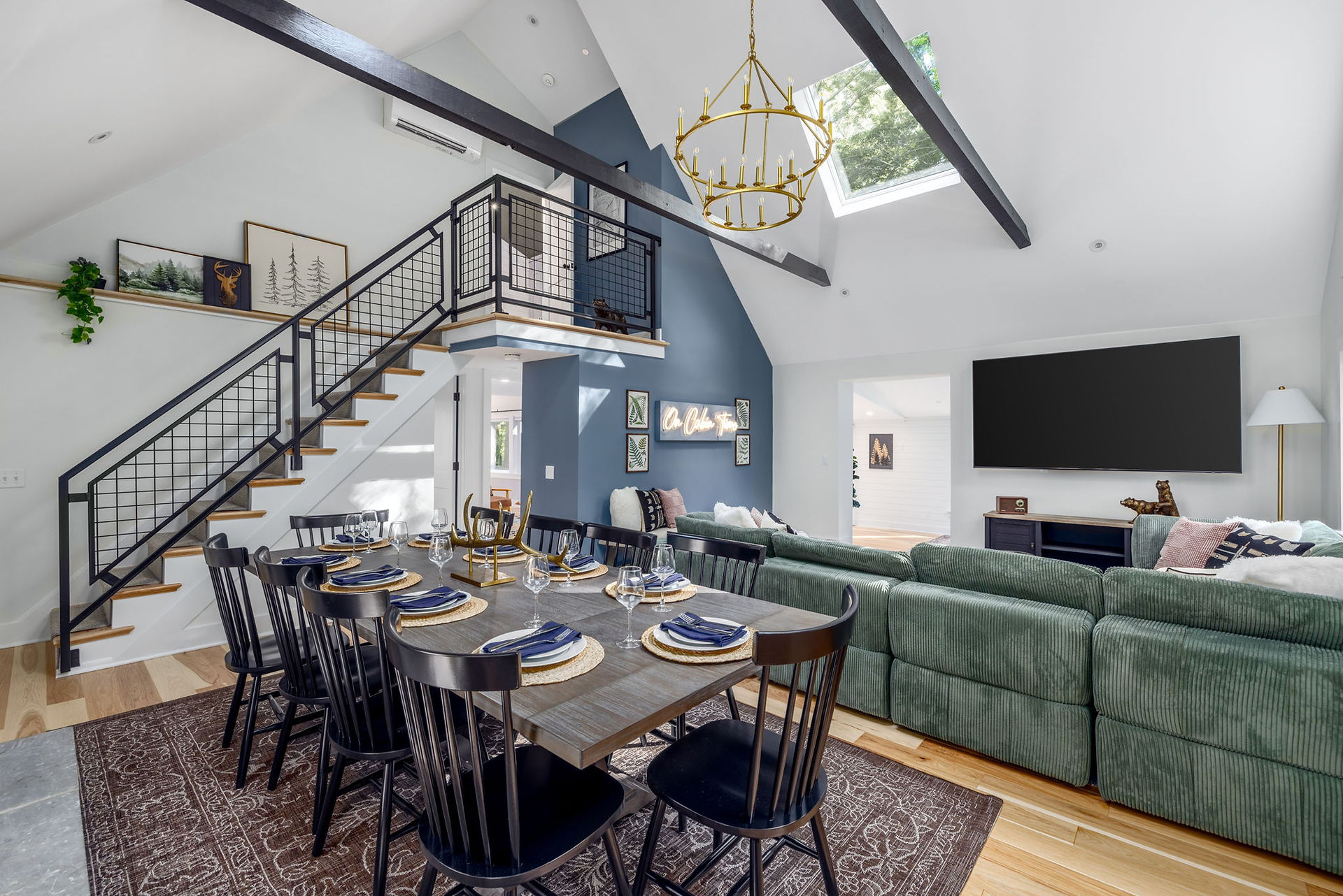 Open living room, with a view of the furnished dining room table with the open staircase leading to the upper level.