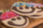Smiling face cookies with colorful sprinkles on top, close up view.