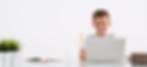Young boy smiling at his laptop during online lesson