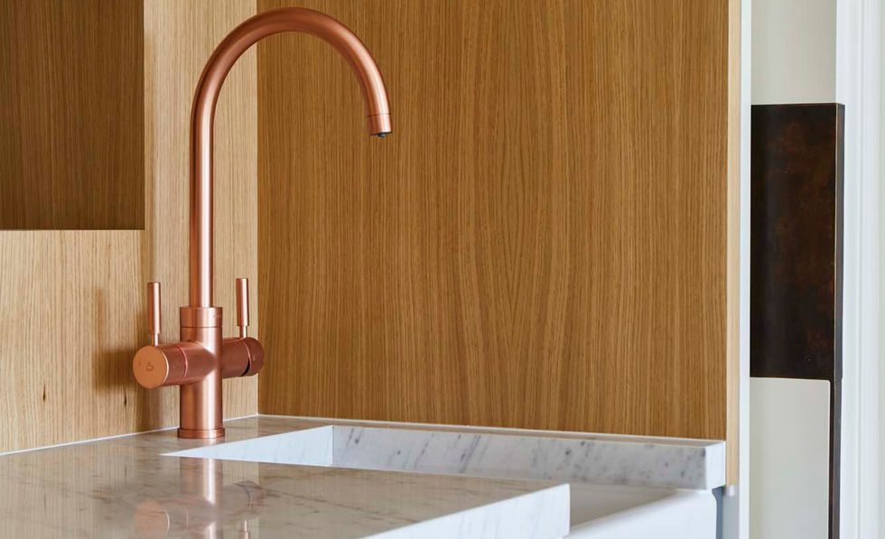 A modern kitchen with gray cabinets and a copper faucet. A farmhouse sink is set into the countertop. The kitchen is well-lit and features plenty of storage space.