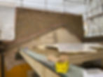 Construction site with exposed brick wall and wooden beams. Yellow "Spectre" screw box in foreground, scaffolding covered in white tarp.