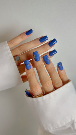 Hands with blue square nails and subtle glitter