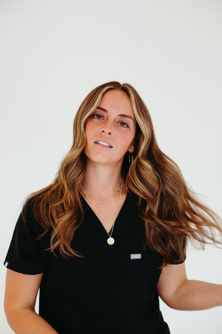 Woman with wavy hair in black scrubs