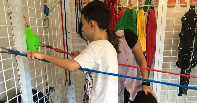 criança segurando em elasticos na fisioterapia
