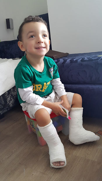 Menino sorridente com gesso, usando uniforme de futebol