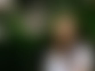 A girl posing in front of leaves and flowers.