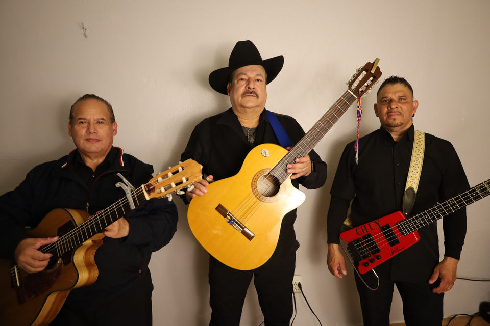 Mariachi trio portrait featuring guitar, guitarrón, and vihuela in traditional charro attire.