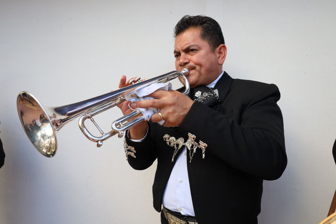 Mariachi trumpet player performing solo in traditional charro suit during a live event.