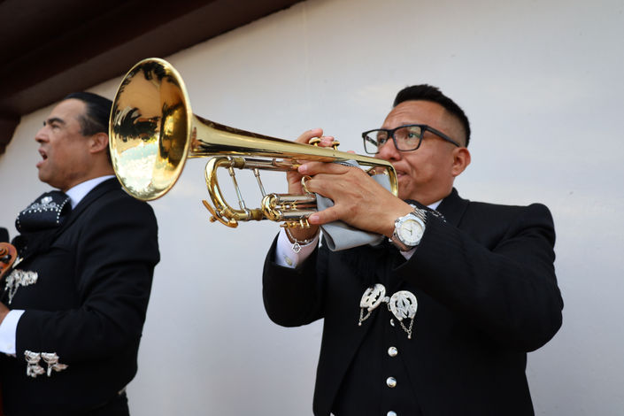 Mariachi trumpet player performing in a traditional black charro suit