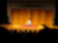 Cena de uma apresentação de rakugo, arte que dá base para a história de Akane Banashi. Aqui, vemos um apresentador (rakugo-ka), sentado no palco, preparando-se para apresentar sua história