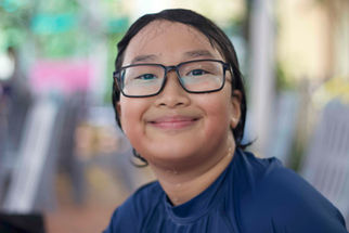 Học viên đang mỉm cười sau buổi học bơi tại Australia Swim School Thảo Điền, mặc áo bơi màu xanh đậm và đeo kính