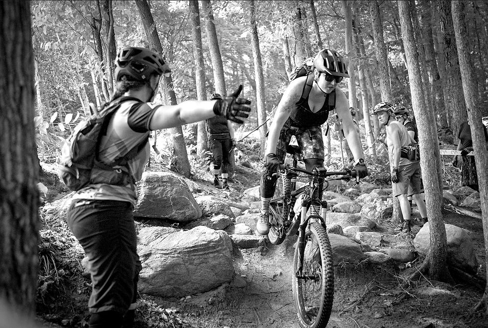 A mountain bike coach guides a rider through a rock garden