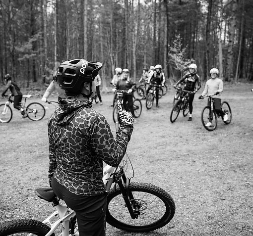 A mountain bike coach calls out instruction to a group of riders