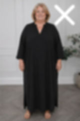 Smiling woman in a long black dress stands indoors against a light wall, with a large white X overlay in the upper right.