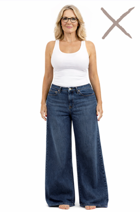 A hourglass woman stands with glassed in low rise palazzo jeans