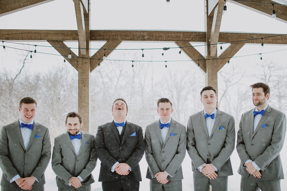 Groom in dark grey suit and groomsmen in grey suits from Moore’s.