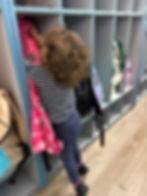 A toddler hanging up her coat