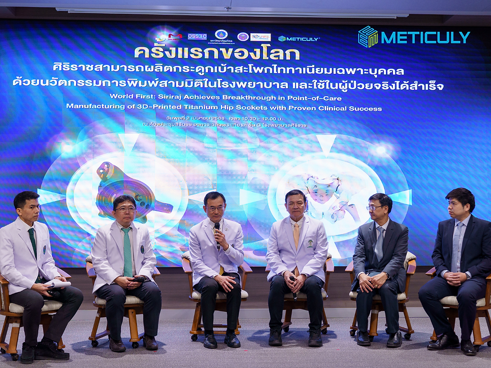 Six men are seated in a row on a stage with upholstered chairs. Behind them, a large screen displays the headline 'ครั้งแรกของโลก' in Thai and 'World First' in English, along with other text and a graphic. The men are dressed in jackets and shirts, suggesting a formal event or presentation. The setting appears to be an auditorium or conference room.