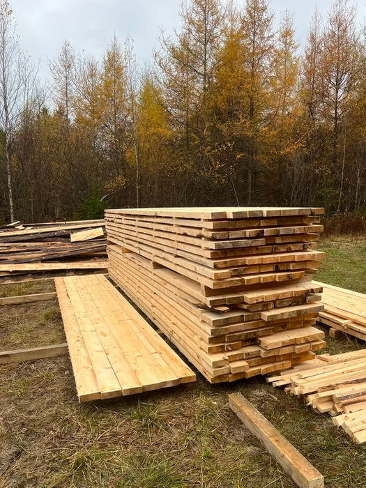 Empilement de planches de bois produites par une scierie mobile sur mesure