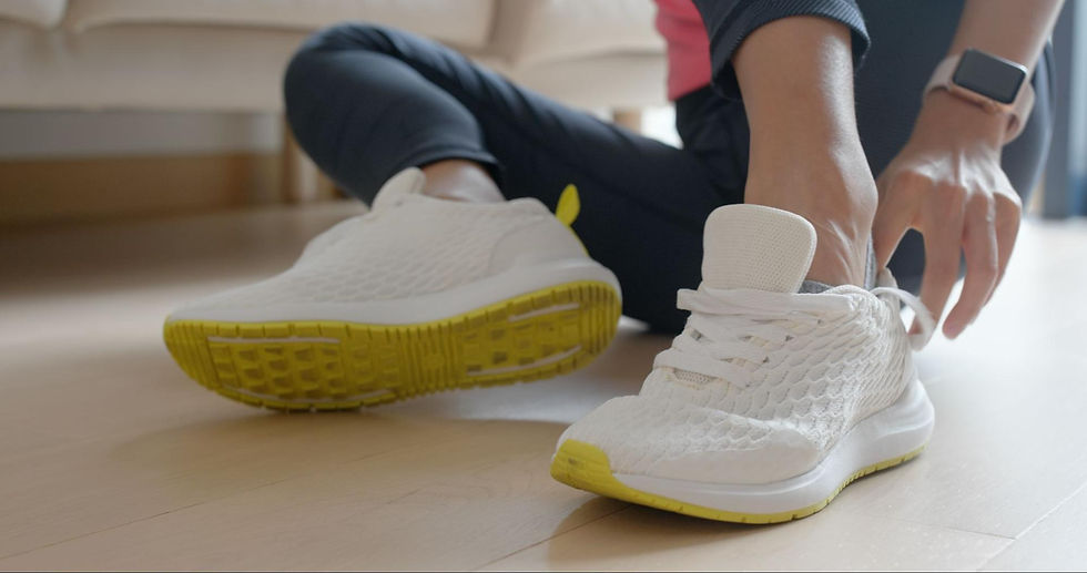 Person putting on cushioned shoes while sitting on the floor.