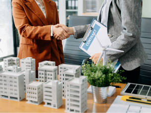 Business people shaking hands in front of real estate models.