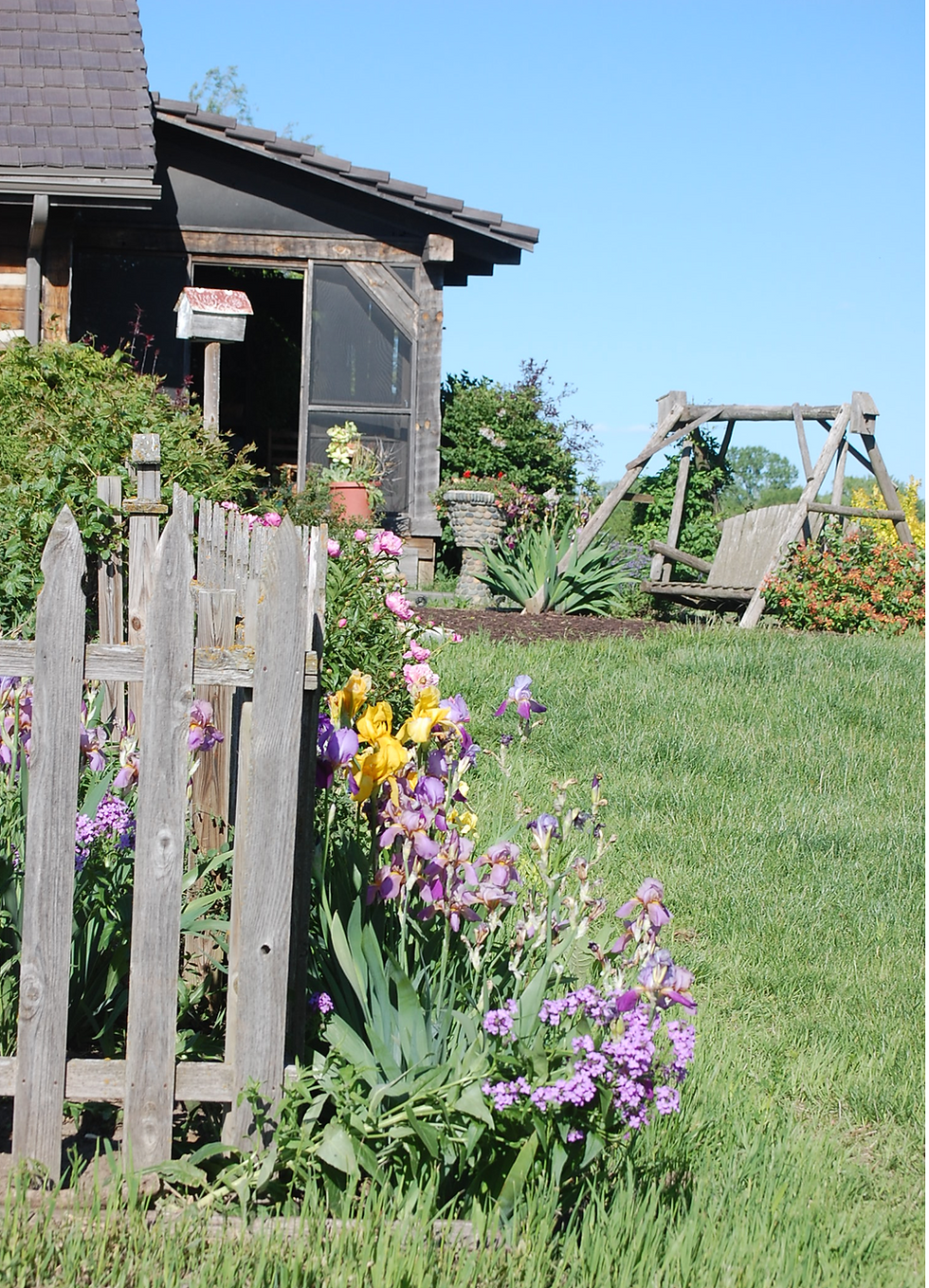 Flowers blooming in front of the swing and side porch.