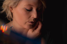 Portrait. Lara mit gesenktem Blick und Licht von der Seite mit farbigem Reflex an der Schulter.