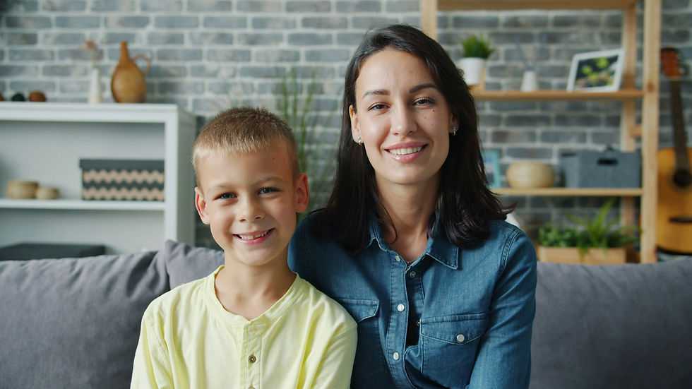 Smiling mom and young son sitting together on a couch, ready to talk about puberty