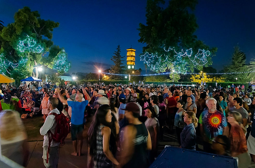 Families dancing at a free summer evening concert under string lights in Pasadena's Memorial Park