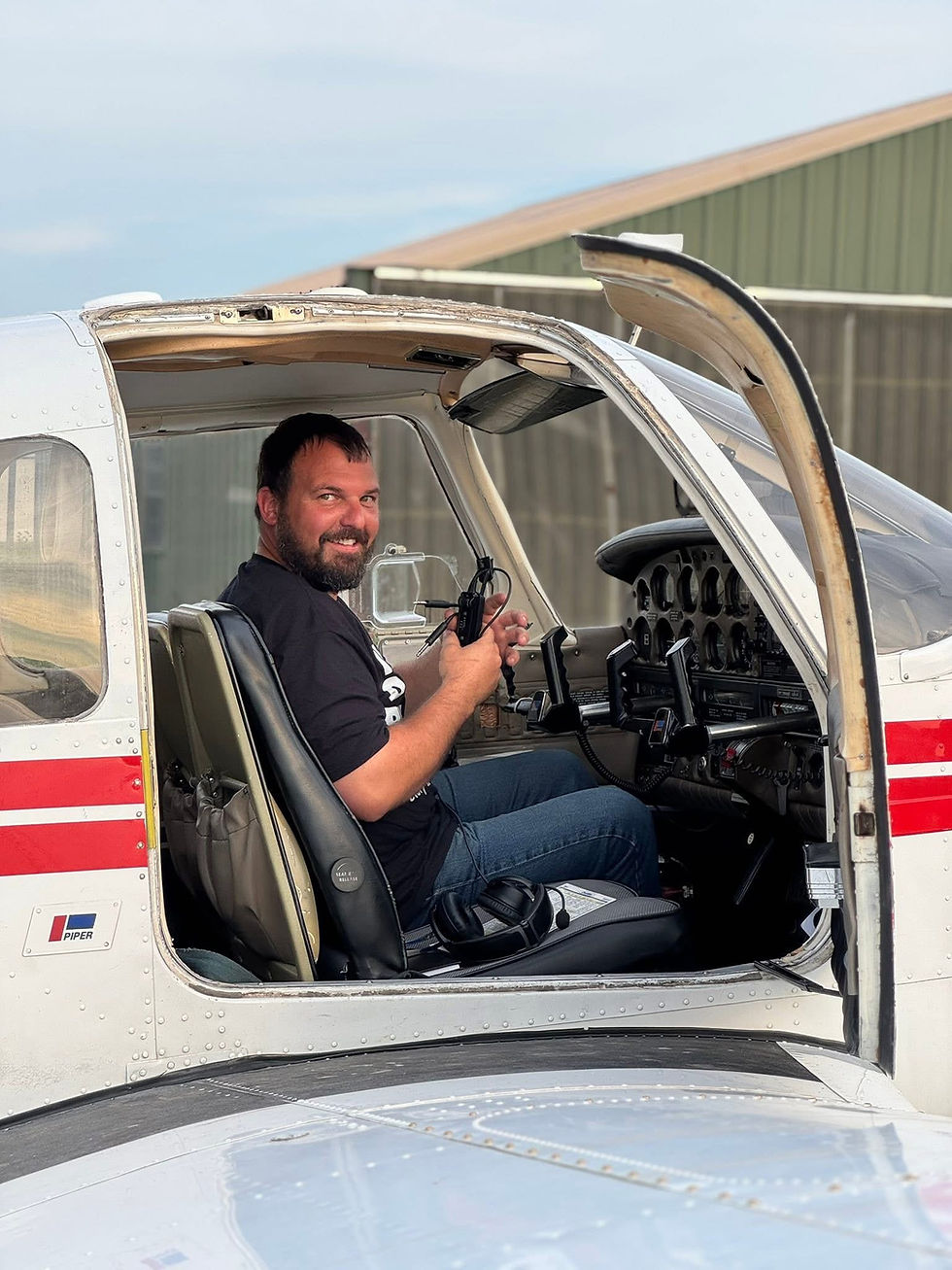 Man smiling in the cockpit of a small white airplane