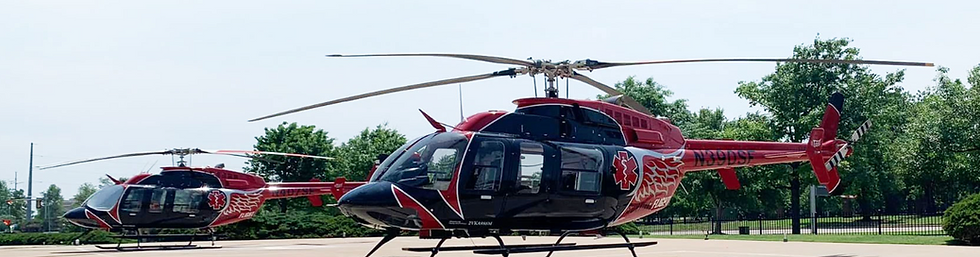 Two red and black helicopters parked on an airfield.