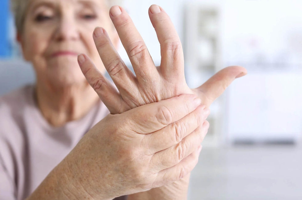Elderly woman gently stretches her fingers in a bright indoor setting, with a calm blurred background.
