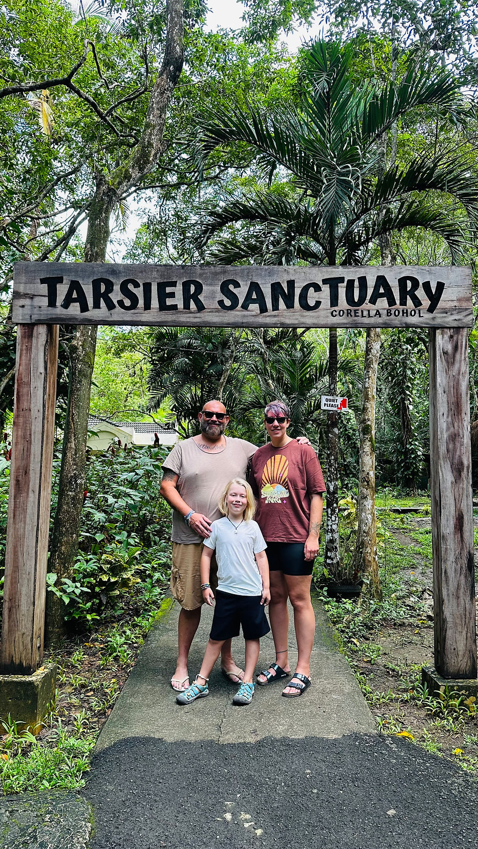Mum, Dad and child under the Tarsier Entrance sign 
