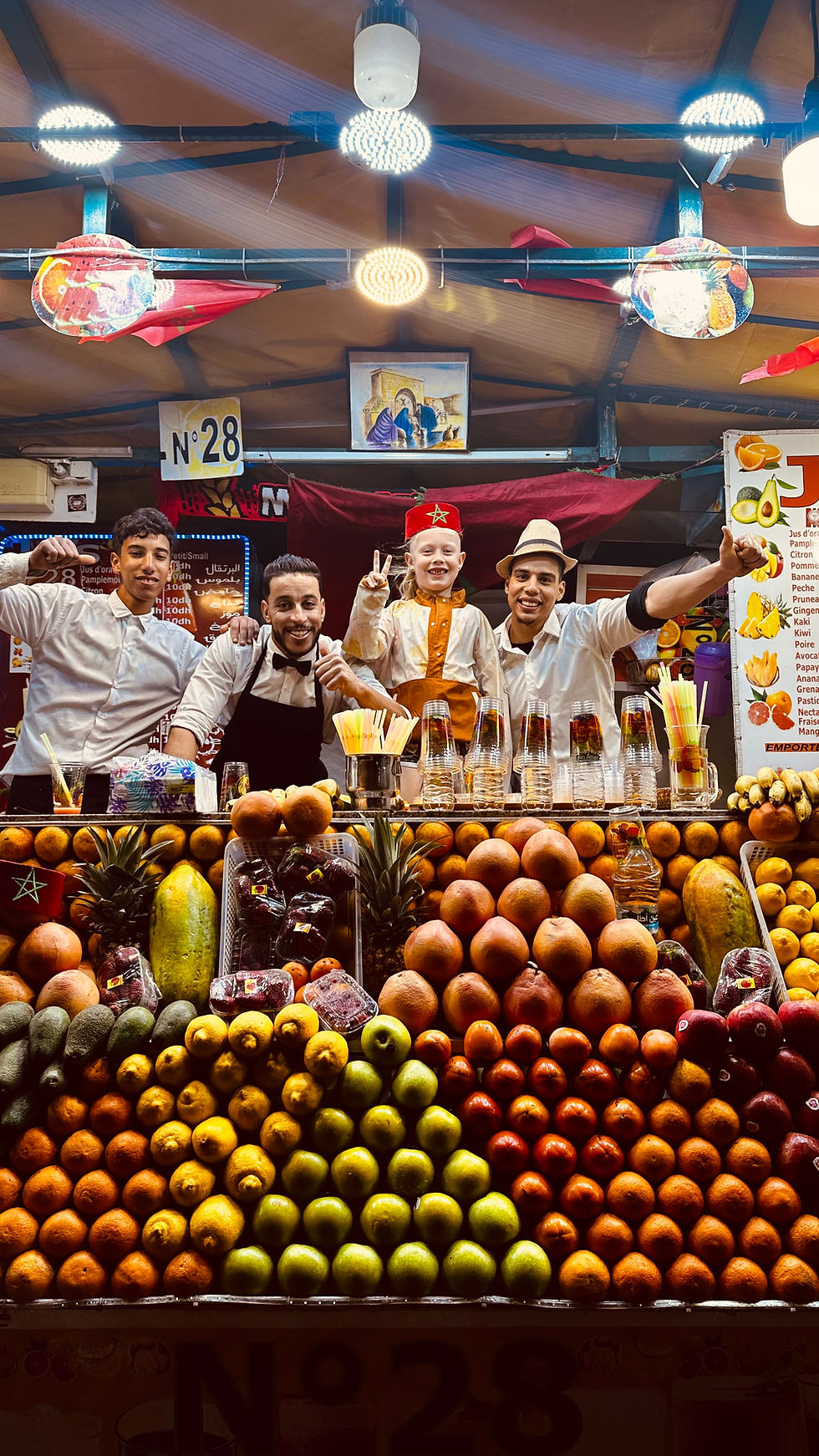 3 men and 1 boy behind a fruit stand