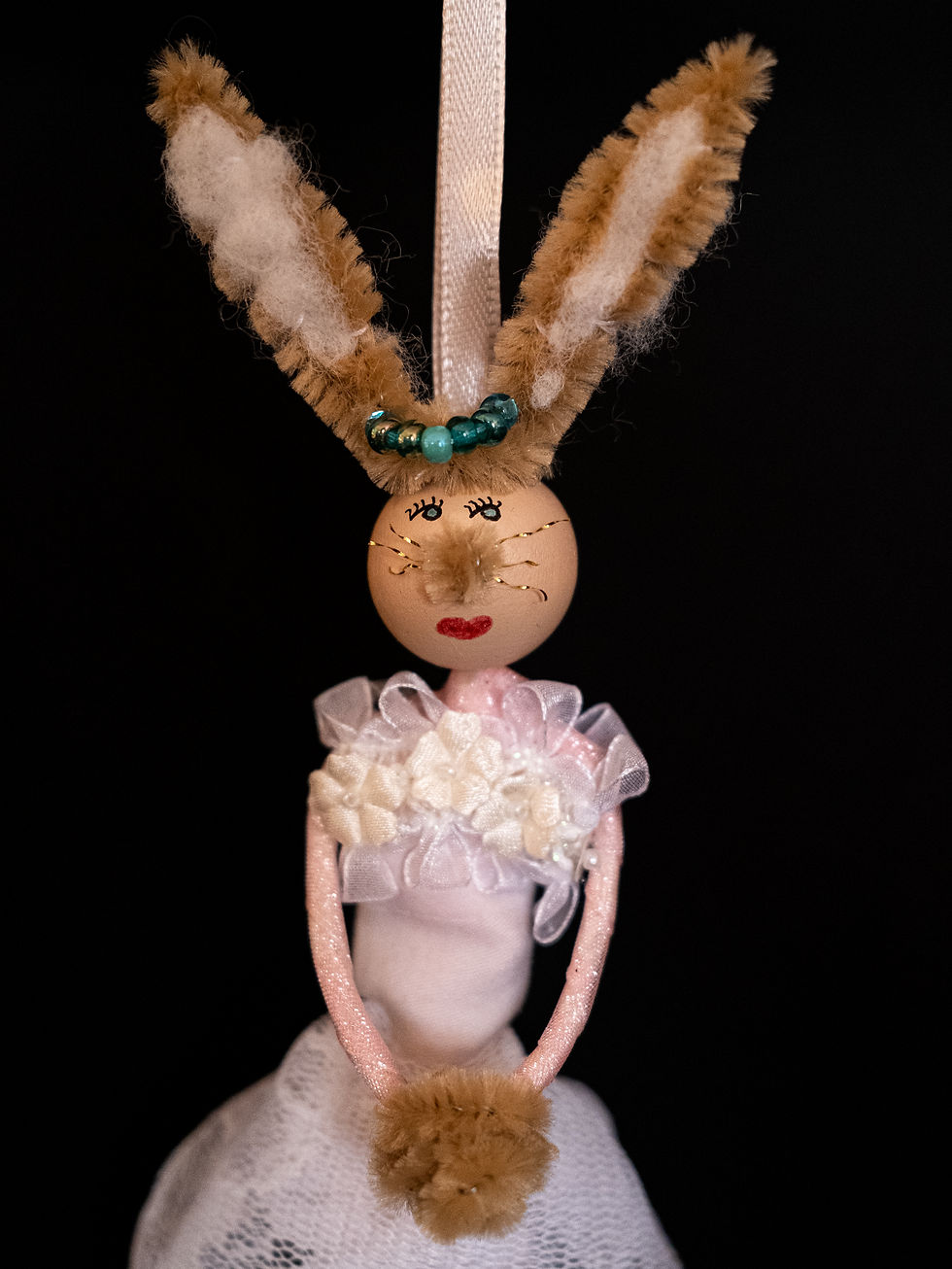 rabbit doll wearing white and pink dress with lace details close up