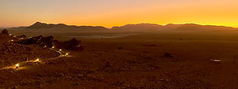 Namib Outpost is located in 7,000 hectares of nature reserve deep in the Namib Desert, it offers a secluded retreat in the heart of Namibia's vast and awe-inspiring desert. Located within a private nature reserve, the lodge provides an ideal base for exploring the nearby Sossusvlei and Sesriem Canyon.
Surrounded by dramatic landscapes, the outpost has a refreshing swimming pool, perfect for cooling off after a day of adventure. The lodge's restaurant serves delicious local cuisine, showcasing the flavours of Namibia. Unwind on the terrace, enjoying panoramic views of the desert as the sun dips below the horizon.
Each house has a comfortable interior, private decks, and modern amenities, so guests can relax in style. The unique design of the houses ensures stunning views of the surrounding desert. They are comfortable and stylish, with thatched roofs, glass-fronted doors and windows overlooking this vast "empty place", the real meaning of the word, Namib. Each house has its own private sleeping deck and sun terrace shaded by thatched roofing.
Whether you're exploring the iconic dunes, going on a game drive, or simply seeking solitude, Namib Outpost provides a truly unforgettable experience in the heart of Namibia.