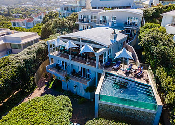 Periwinkle Guest Lodge is situated on Beachy Head Drive, in Plettenberg Bay, directly across the road from the Robberg Blue Flag Beach, a safe swimming beach.
The Lodge is on three levels and has breathtaking views of the famous Robberg Peninsula, the Tsitsikamma Mountains and the sea. There's a wellness centre and sauna as well as a restaurant and a small gym. The fantastic deck is the ideal spot to relax with a drink and watch the sun go down. You're only a short distance from plenty of shops, restaurants and galleries in the town.
All the rooms are stylishly decorated. Six of the seven rooms have balconies where you can enjoy the panoramic view from the Tsitsikamma Mountains. Each room has tea and coffee-making facilities, television, WiFi and lovely views.