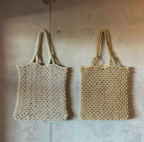 two crocheted bags are hanging on a concrete wall