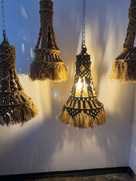 a row of macrame lamps hanging from a chain