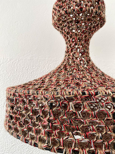 a close up of a knitted object against a white wall