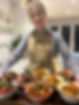 A woman with a brown apron holding Corporate catering dishes