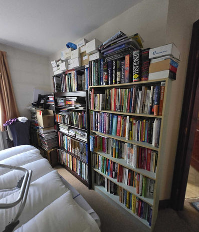 Room with large bookshelves stacked with books, files and storage boxes requiring room clearance.