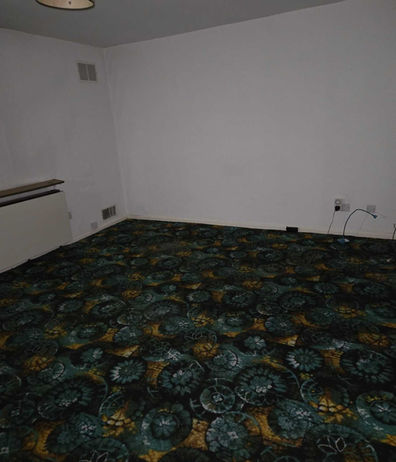 Unfurnished room with dark green patterned carpet requiring property clearance services.