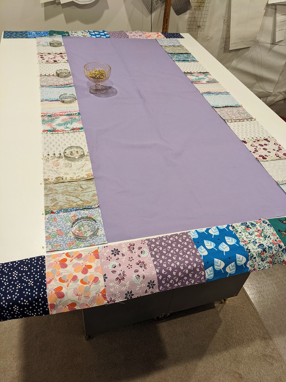 All strips of squares have been sewn together. The two strips running along the long length of the center rectangle have been pinned to the center right sides facing. The ends of the square strips are even with the rectangle. The remaining top and bottom strips sit off to the sides, unpinned.